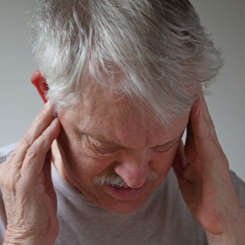 older man holding his head in pain