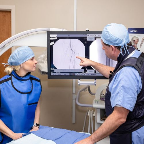 surgeon and nurse viewing a screen during a genicular artery embolization procedure