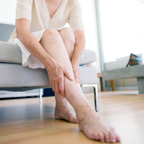 older woman examining her varicose veins in her living room