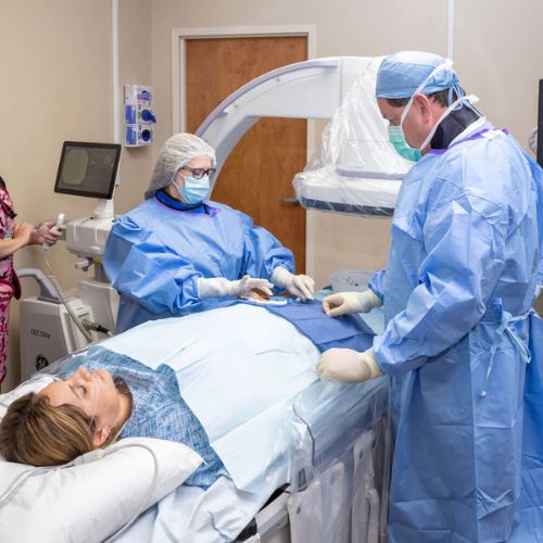 surgeon and nurse performing genicular artery embolization on a patient