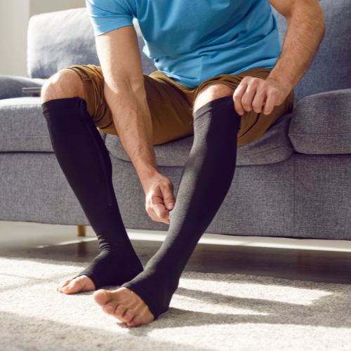 man putting on compression stockings to relive his CVI symptoms