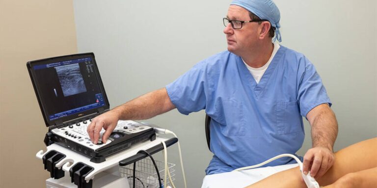 Dr. Christopher Pollock examining a patient's veins