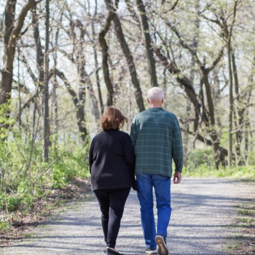 Older couple walking a trail through the woods