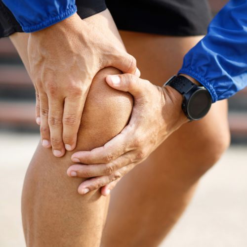 man holding his knee in pain while on a run