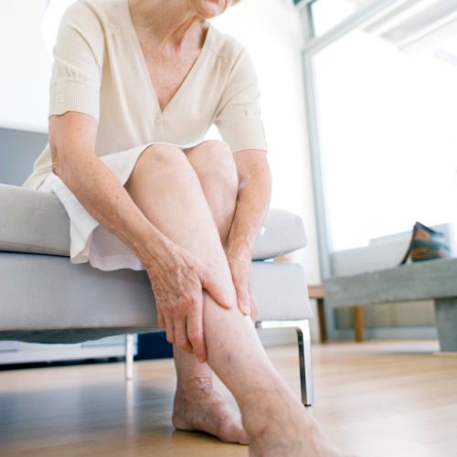 woman rubbing her aching leg