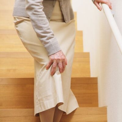 Woman holding her knee due to chronic limb pain while going down stairs