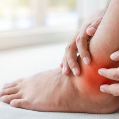 man rubbing his ankle which is highlighted to emphasize pain