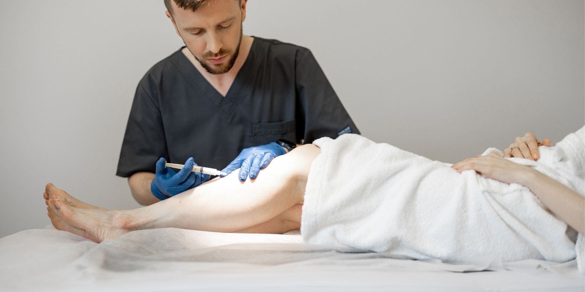 Vascular surgeon performing sclerotherapy on a patient
