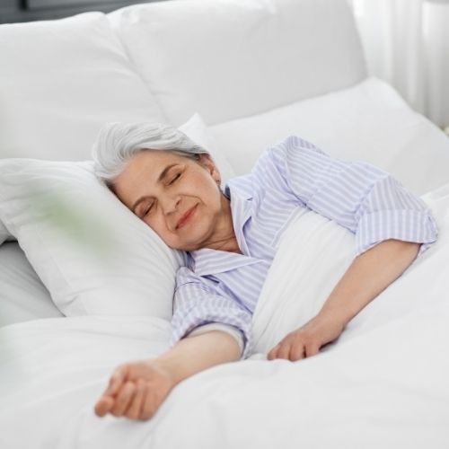 older woman sleeping in bed to support carotid artery surgery recovery